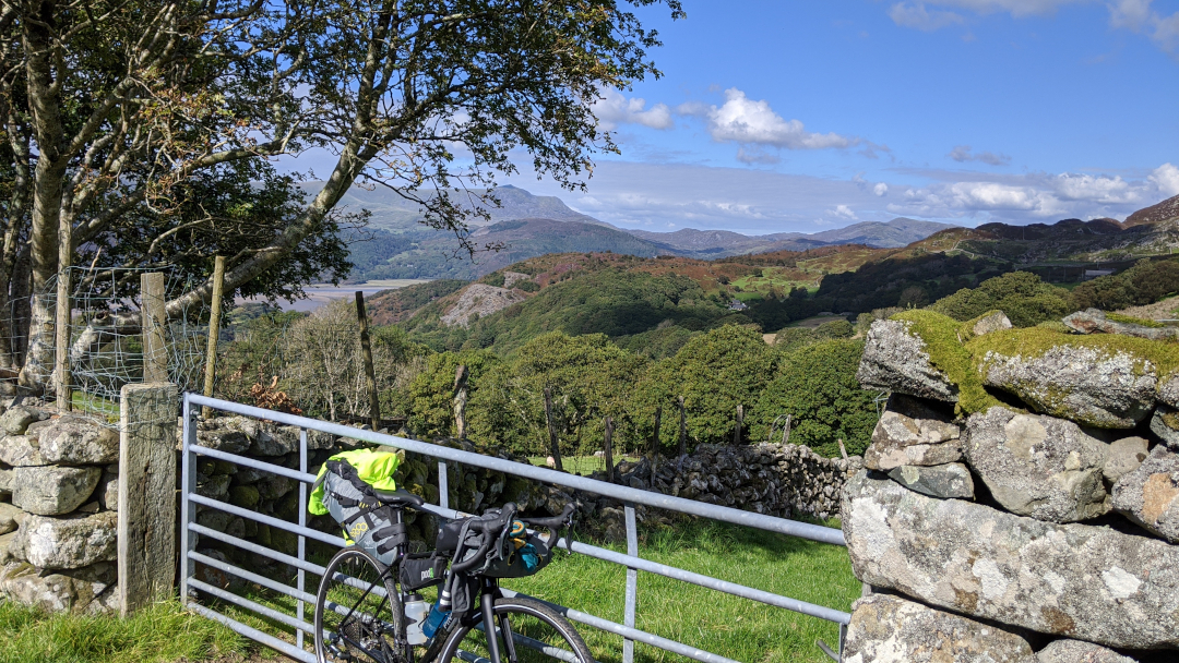 Bike in the foreground, Afon Mawddach and southern Snowdonia hills in the background along a steep ascent